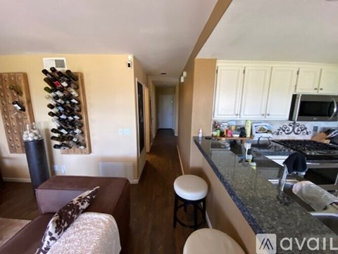 A kitchen with a bar stool and a counter with a microwave on it.