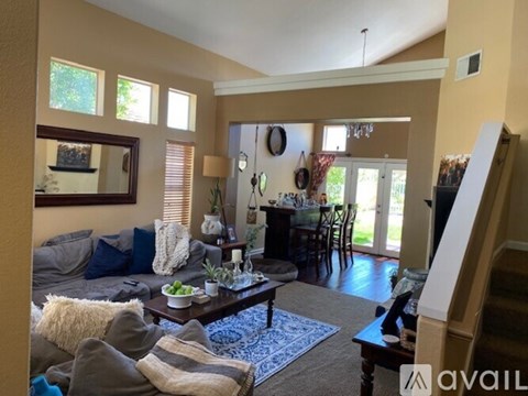 A living room with a grey couch, a coffee table, and a dining table with chairs.