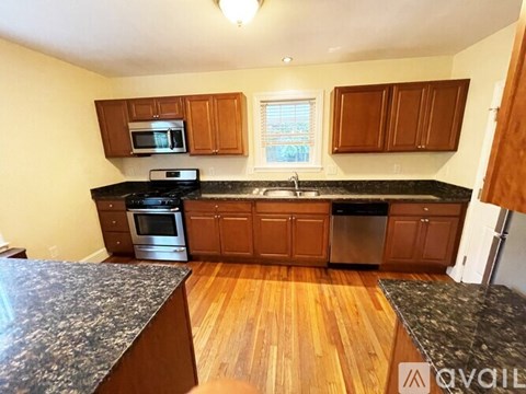 A kitchen with wooden cabinets and black countertops.