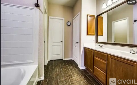 A bathroom with a white tub and wooden cabinets.