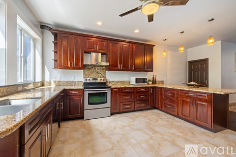 A kitchen with brown cabinets and a marble countertop.