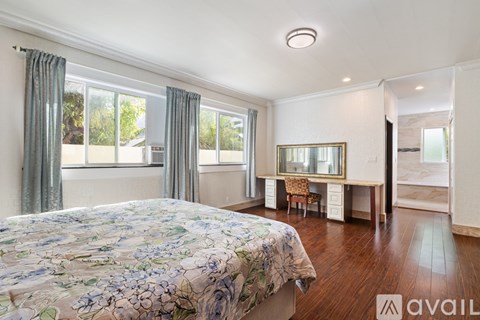 A bedroom with a large bed and a desk with a chair.