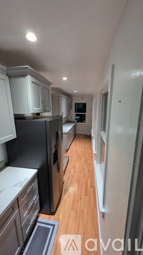 A kitchen with black appliances and wooden floors.