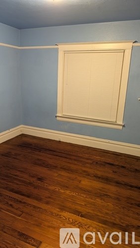A room with a wooden floor and a window with blinds.