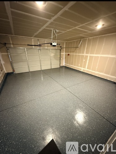 A spacious garage with a closed door and a wall-mounted light fixture.