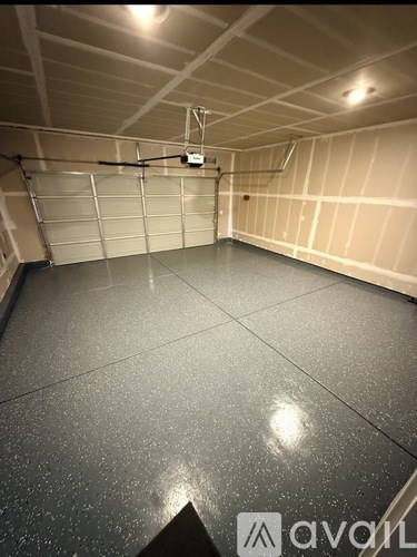A spacious garage with a closed door and a wall-mounted light fixture.