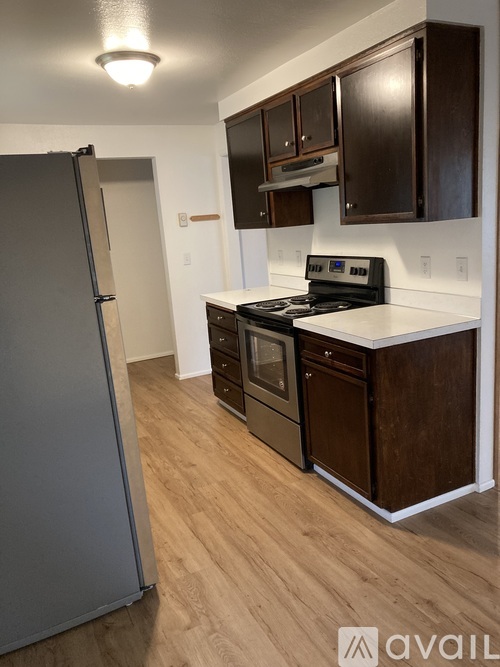 A kitchen with a refrigerator, stove, and cabinets.