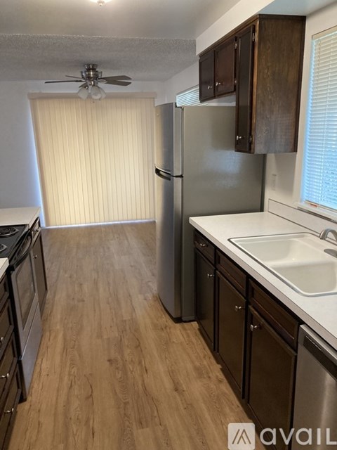 A kitchen with wooden floors and a stainless steel refrigerator.