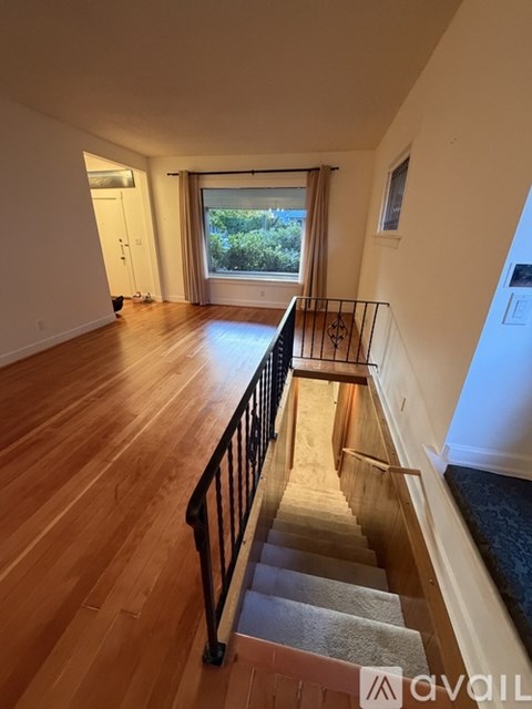 A staircase with a metal railing leads to a window with a view of trees.