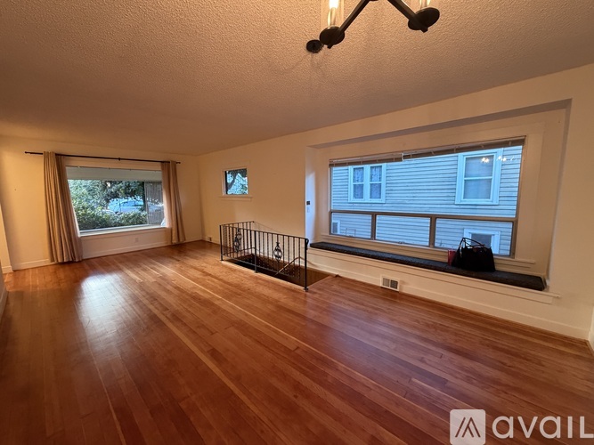 A spacious room with wooden floors and a large window.