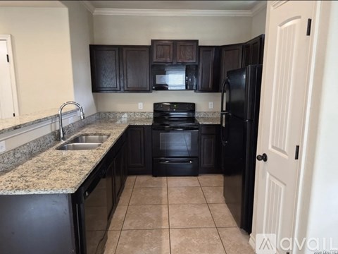 A kitchen with black appliances and brown cabinets.