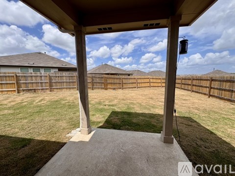 A patio with a roof and pillars overlooking a grassy area.