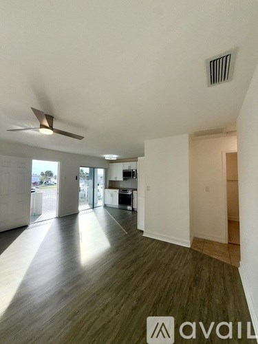 A spacious room with wood flooring and a ceiling fan.