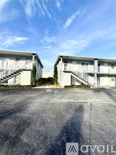 A parking lot with two buildings and a clear sky.