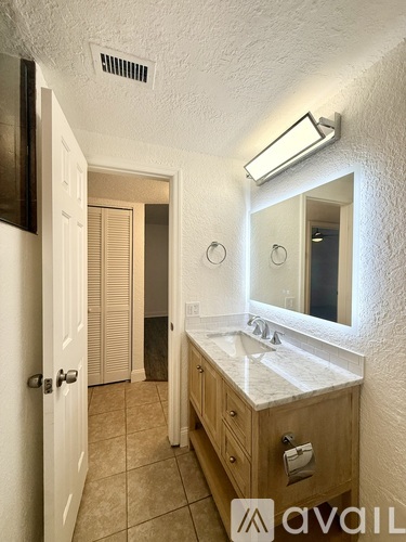 A bathroom with a sink, mirror, and light fixture.