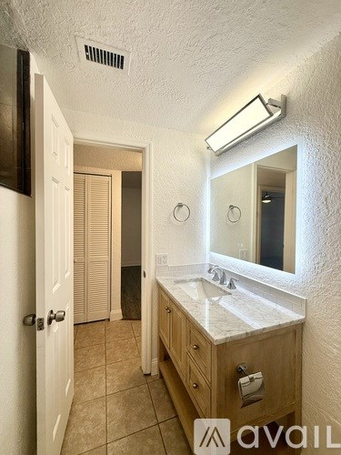 A bathroom with a sink, mirror, and light fixture.