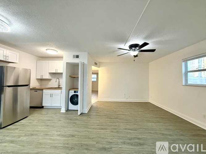 A spacious room with a refrigerator, washing machine, and a ceiling fan.