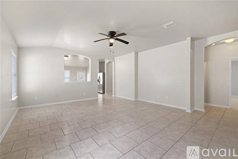 A spacious room with a ceiling fan and tile flooring.