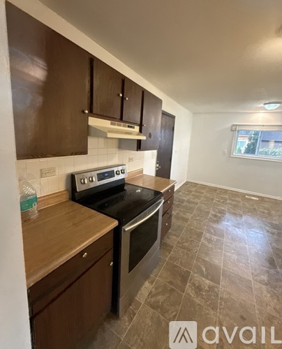 A kitchen with a black stove top oven and wooden cabinets.