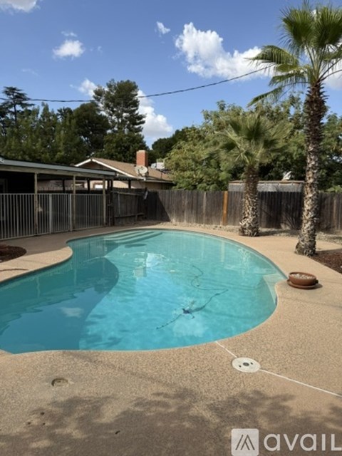 A pool surrounded by a fence and trees.