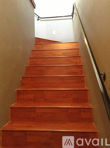 A wooden staircase with a metal handrail.