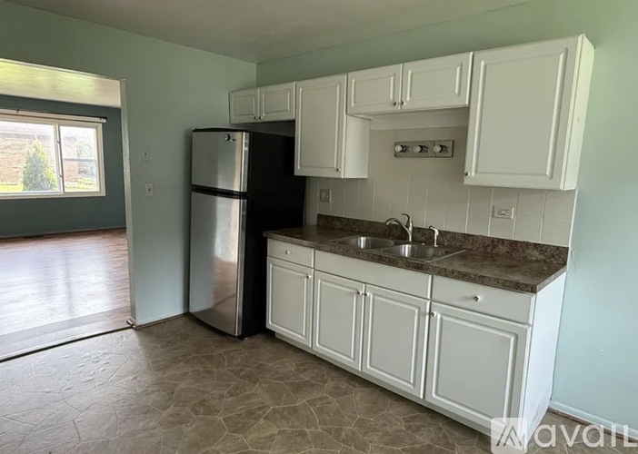 A kitchen with white cabinets and a black fridge.