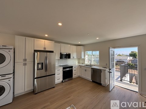 A modern kitchen with stainless steel appliances and wooden flooring.