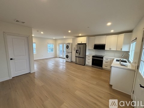 A spacious kitchen with wooden flooring and white cabinetry.