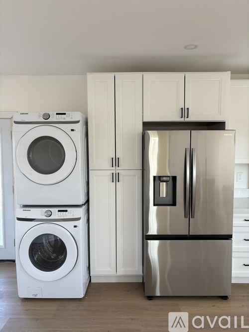 A modern kitchen with a stainless steel refrigerator and white appliances.
