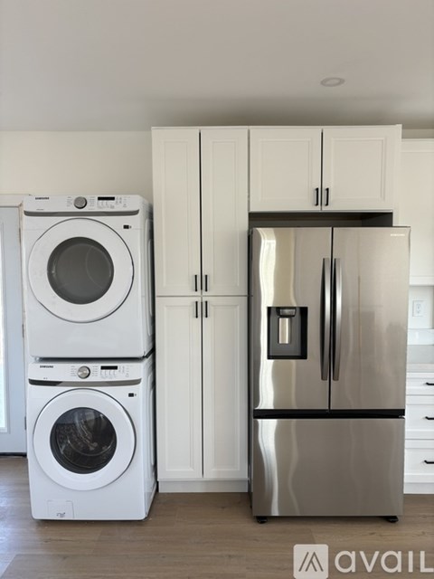 A modern kitchen with a stainless steel refrigerator and white appliances.