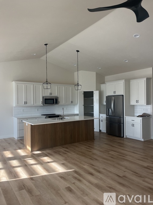 A modern kitchen with wooden floors and white cabinets.