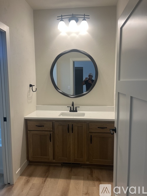 A bathroom with a round mirror and wooden cabinets.