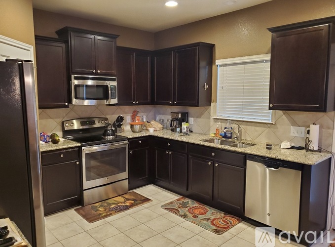A kitchen with brown cabinets and a black refrigerator.