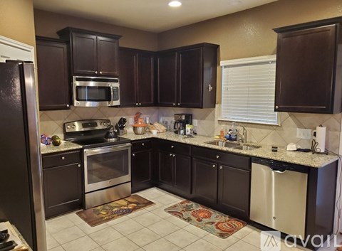 A kitchen with brown cabinets and a black refrigerator.