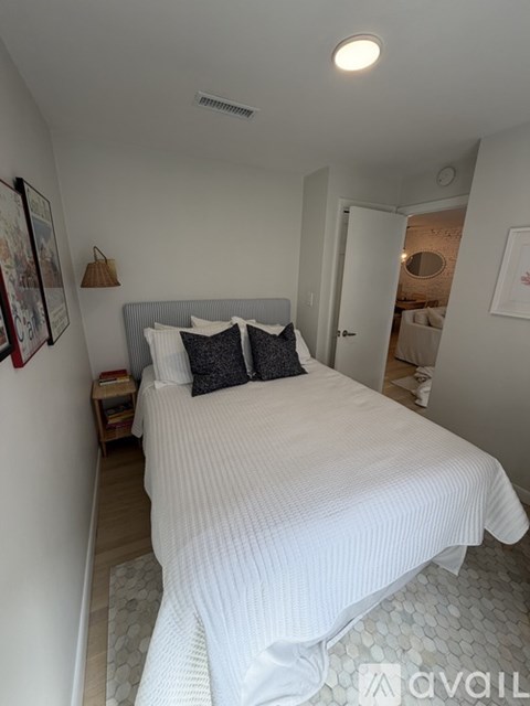 A bedroom with a large bed and a white wall.