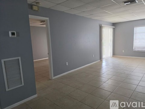 A spacious room with tile flooring and a door leading to another room.