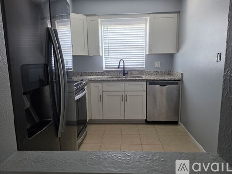 A kitchen with a stainless steel refrigerator and white cabinets.