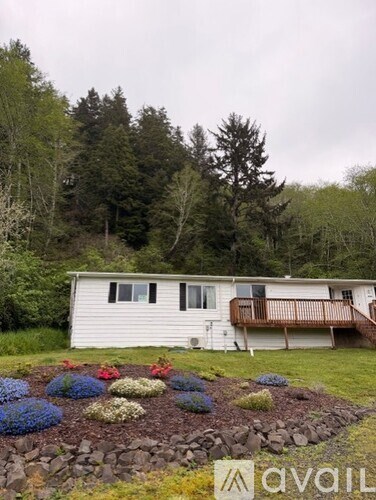 A white house with a deck and a garden in front.