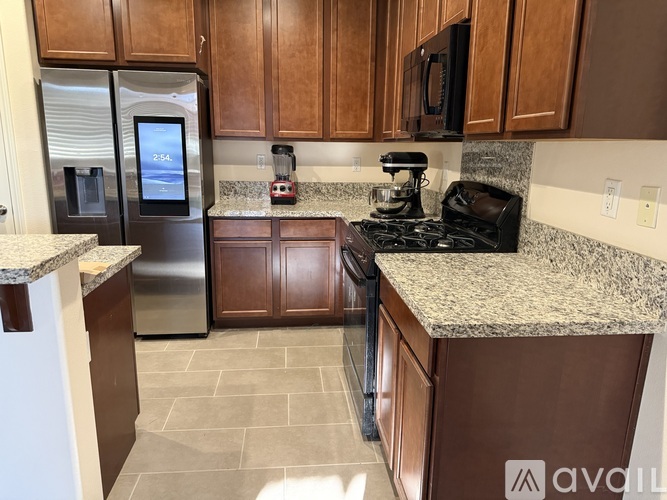 A kitchen with a granite countertop and a stainless steel refrigerator.