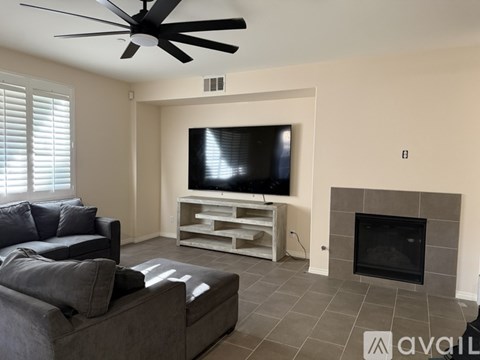 A living room with a grey couch, a television, and a fireplace.