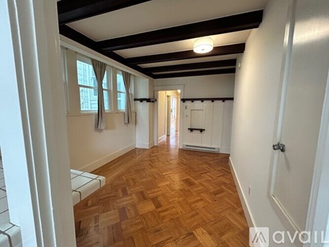 A hallway with wooden floors and white walls.