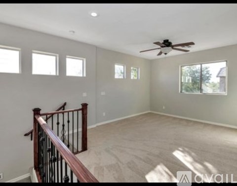 A spacious room with a staircase and a ceiling fan.