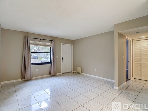 A spacious room with a window, a door, and a tiled floor.