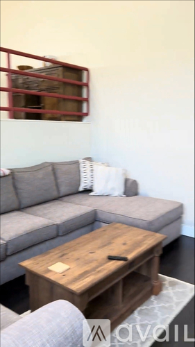 A grey couch with a wooden coffee table in front of it.