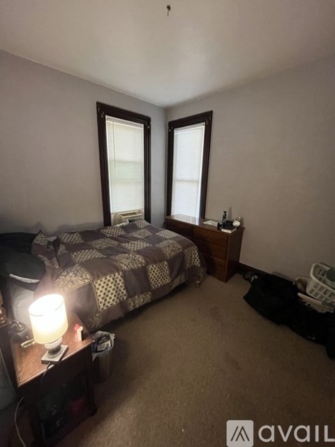 A bedroom with a bed, nightstand, and window.