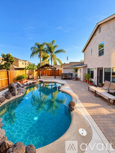 A pool with a stone border and a wooden deck.