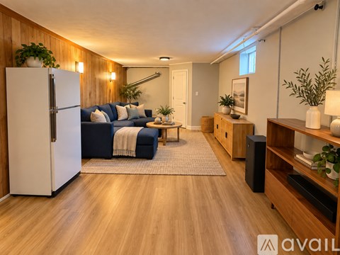 A living room with a white refrigerator on the left and a blue couch in the middle.
