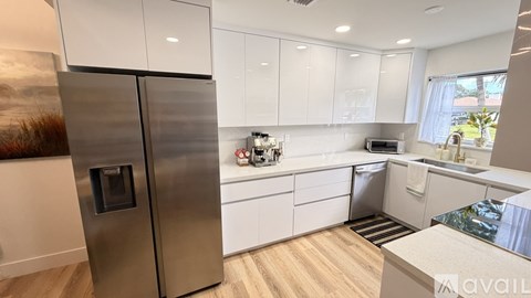 A modern kitchen with a stainless steel refrigerator and white cabinets.