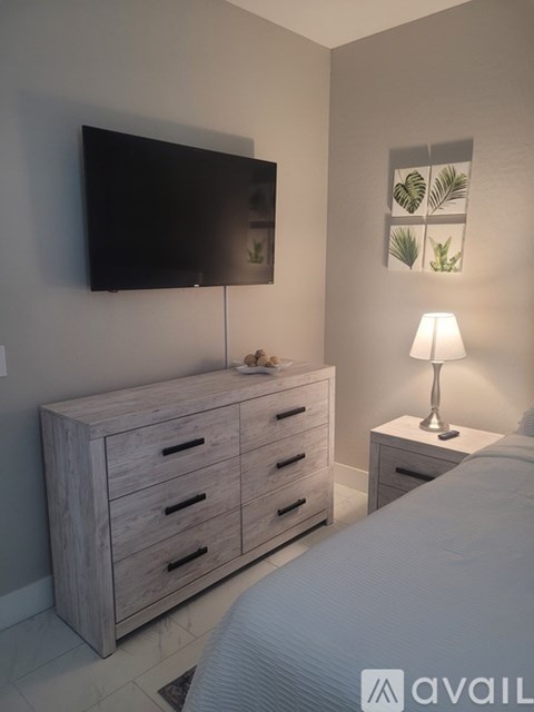 A bedroom with a bed, a cabinet with drawers, and a lamp on a side table.