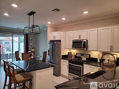 A modern kitchen with white cabinets and black countertops.